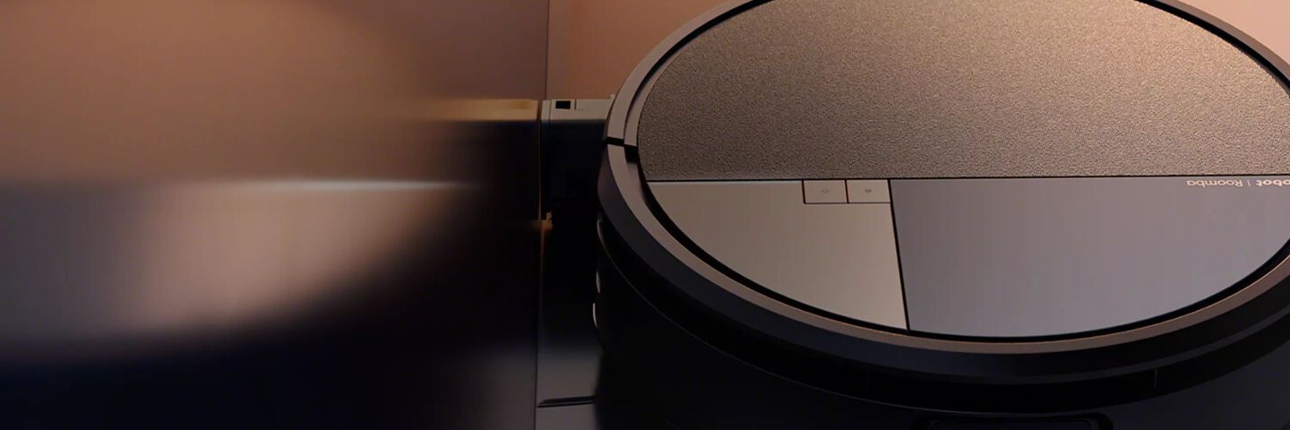 An image of a Roomba robot vacuum against a warm brown background